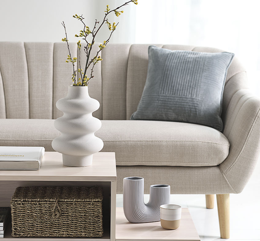 Bright living room with playful vases on coffee table and beige sofa 