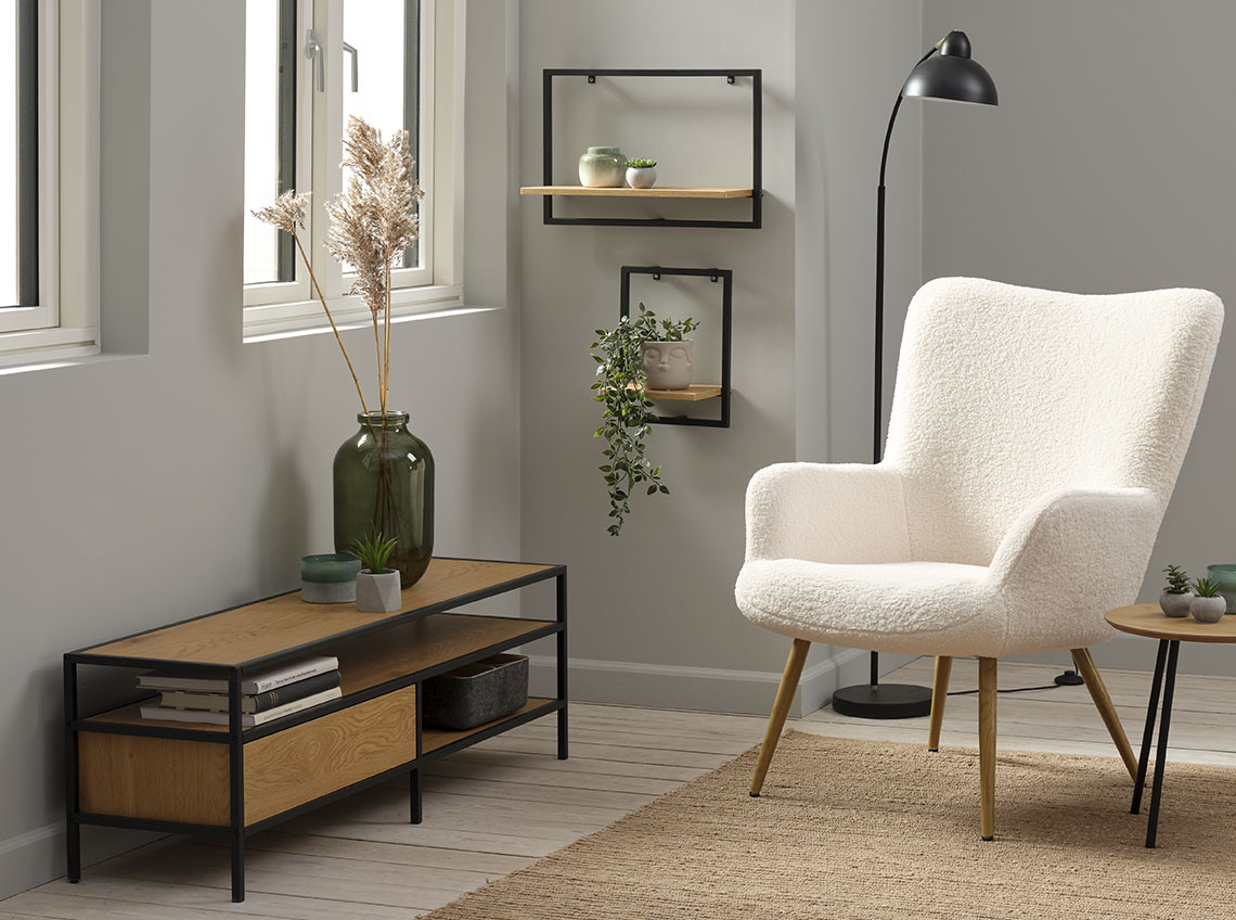 TV unit with storage below a window and next to an armchair 