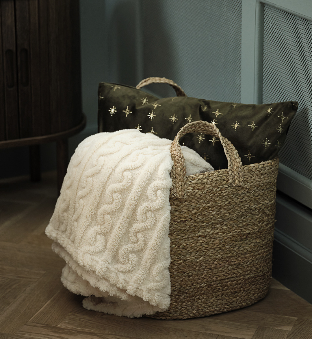 A basket with a soft blanket and a green decorative cushion with gold stars