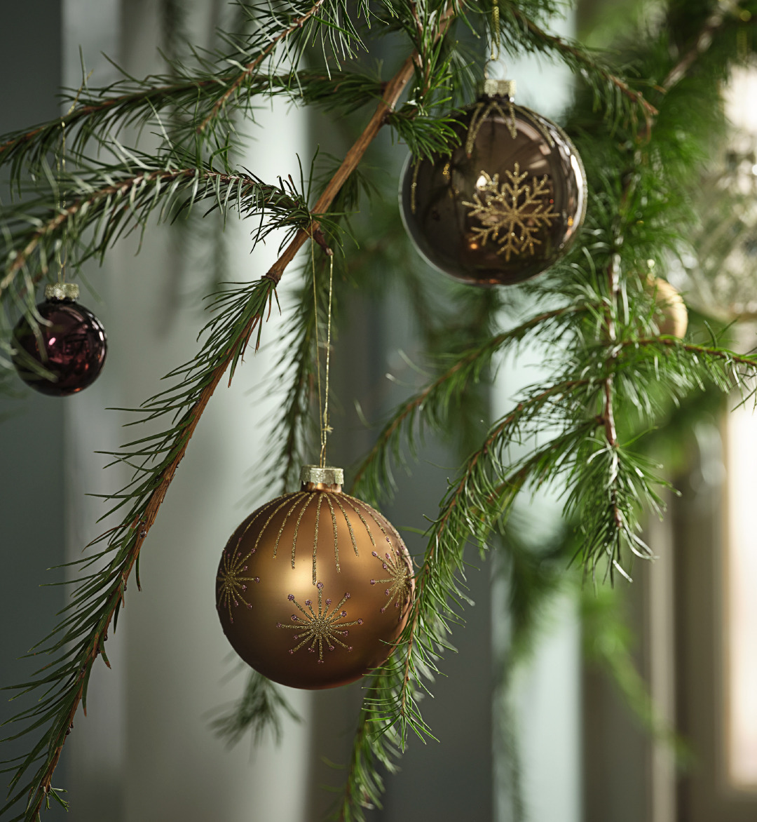 A branch decorated with baubles in earthy tones with glitter