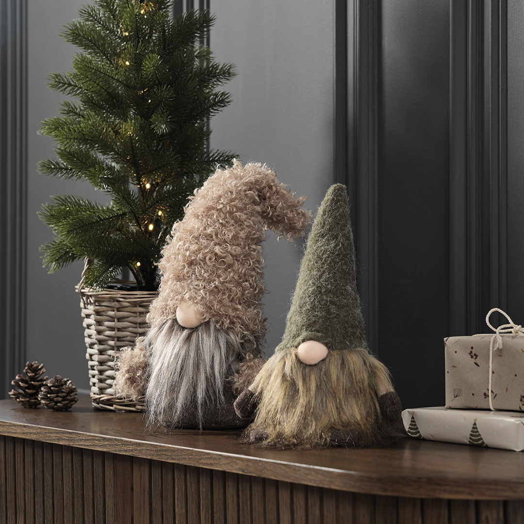 Small decorative Christmas elves in shades of green and brown on sideboard