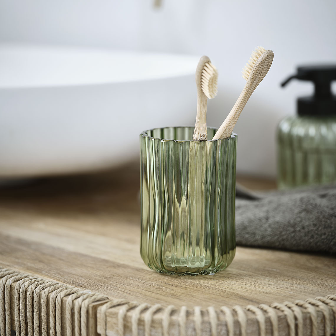 Toothbrush holder in green transparent glass on a bathroom sink