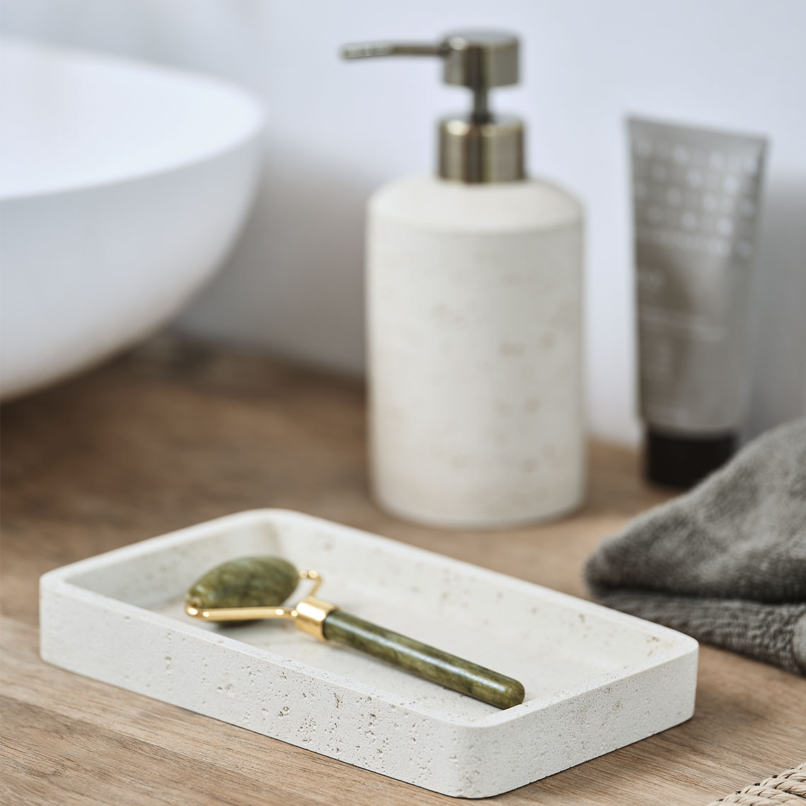 Tray and soap dispenser in beige stoneware on a bathroom sink