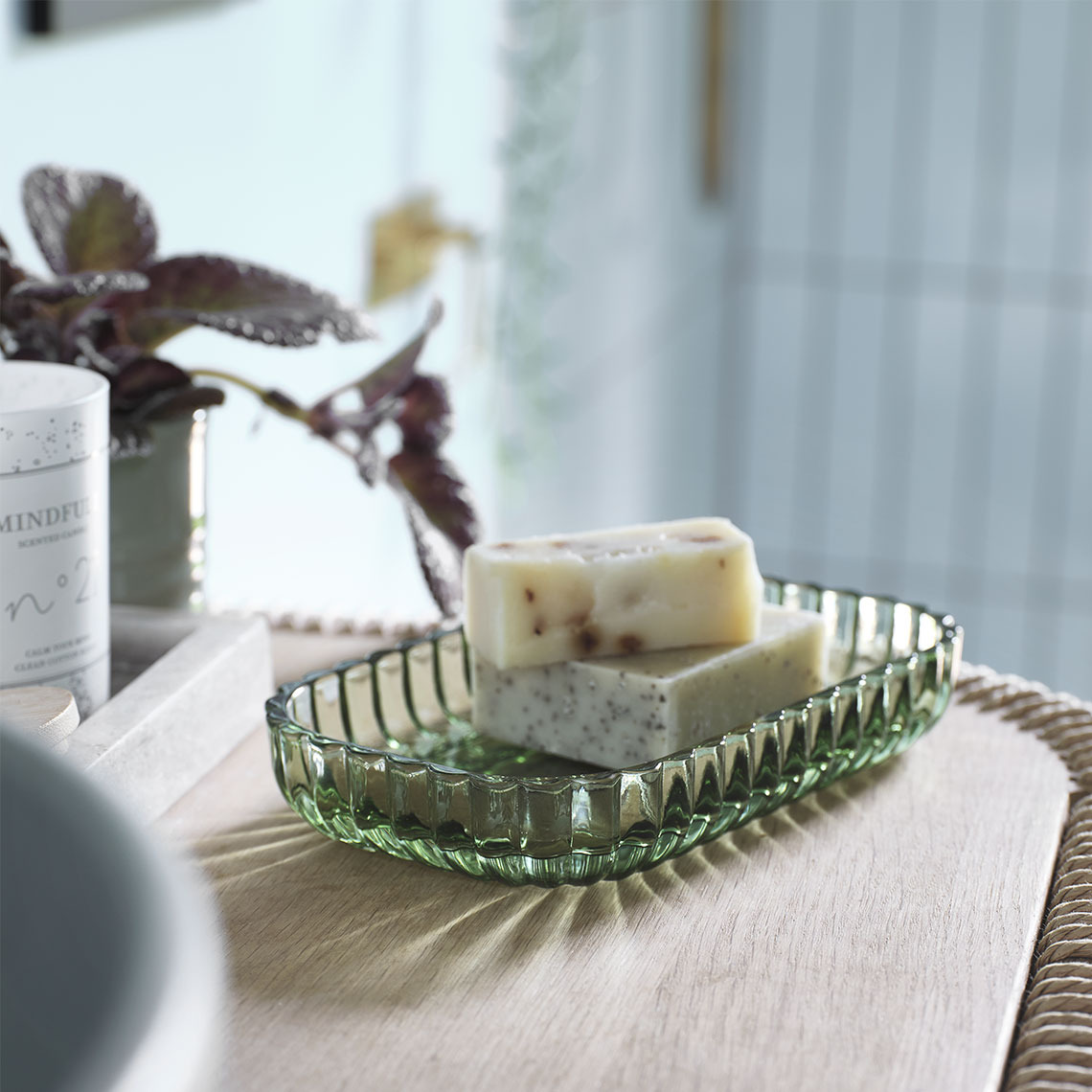 Rectangular tray in green transparent glass with soap on a bathroom sink