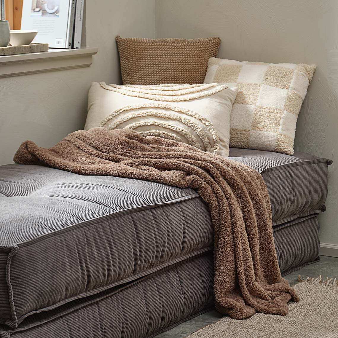 Throw and decorative cushions in Mocha Mousse and beige colours on daybed 