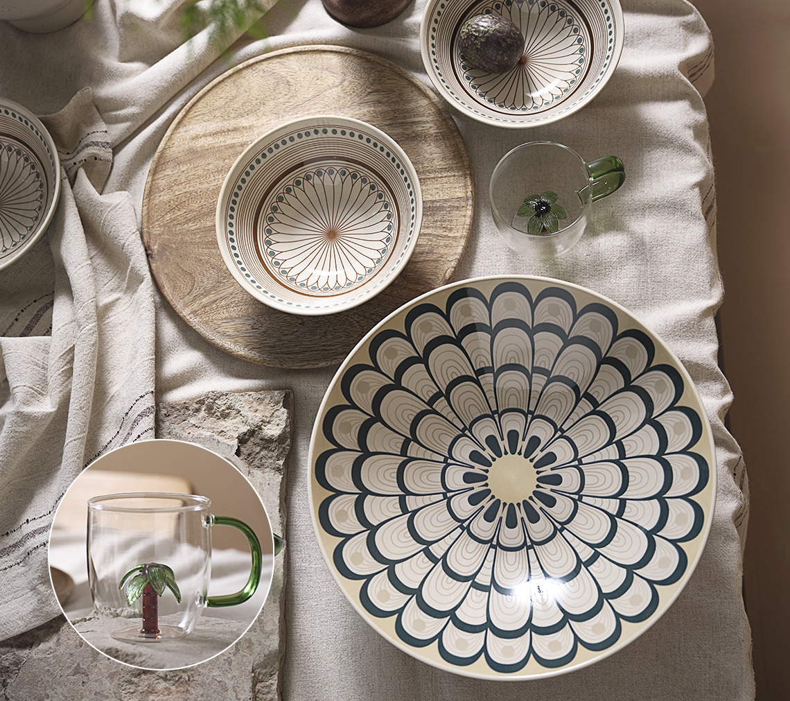 Table set with tablecloth, large bowl, smaller bowl and glass mug with palm tree