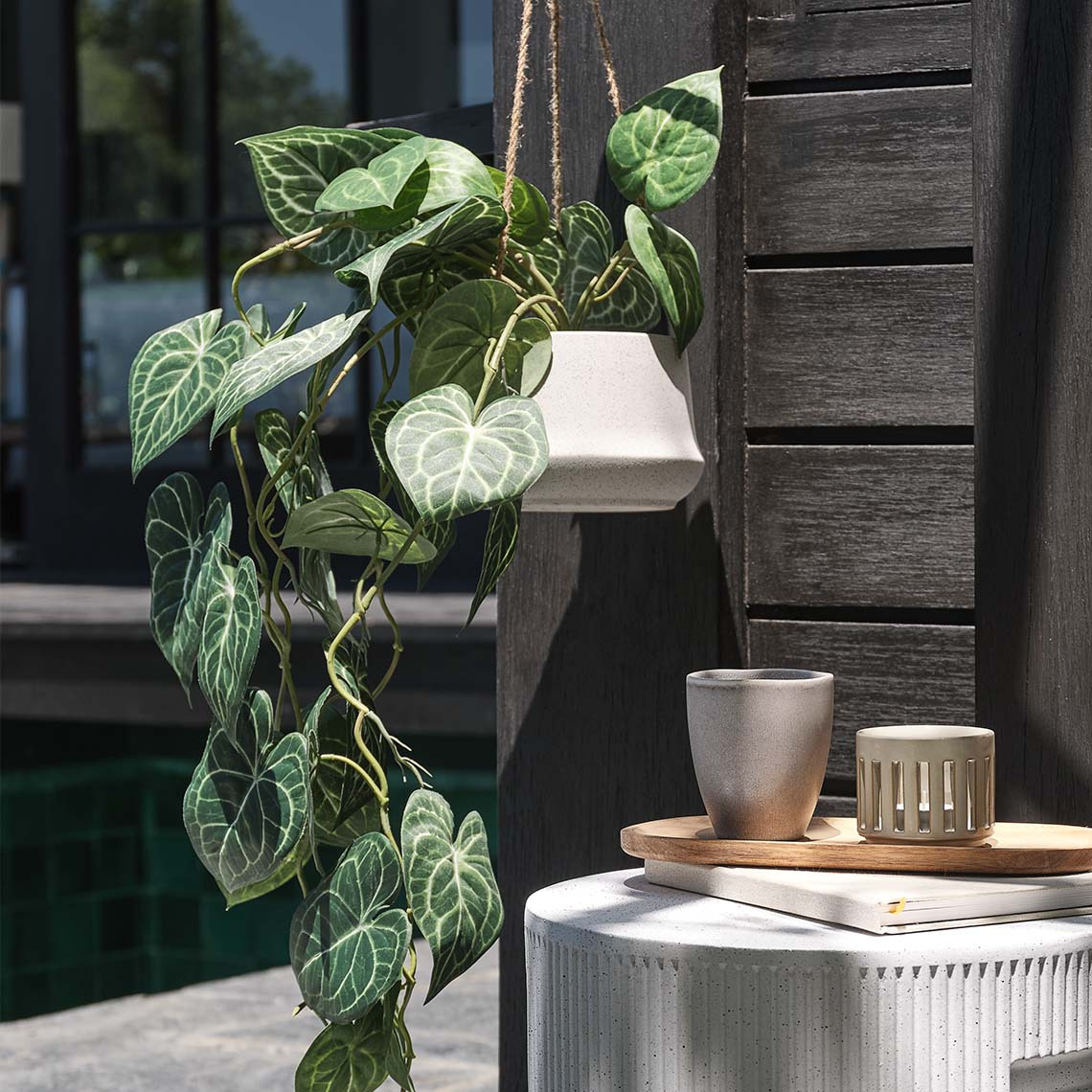 Earthenware garden hanging plant pot with artificial plant on an outdoor patio 