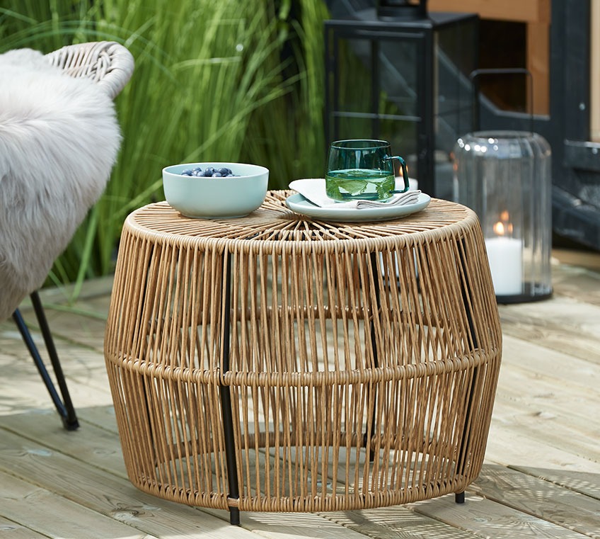 Rattan side table with a bowl and a glass mug