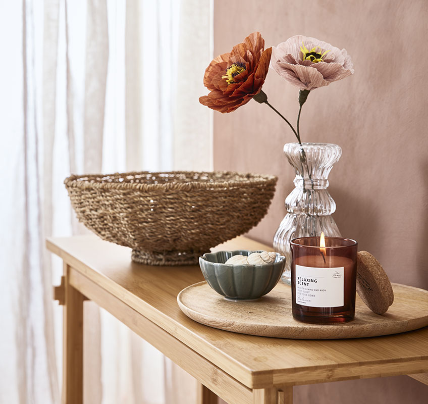 Glass vase, green bowl and scented candle on wooden tray